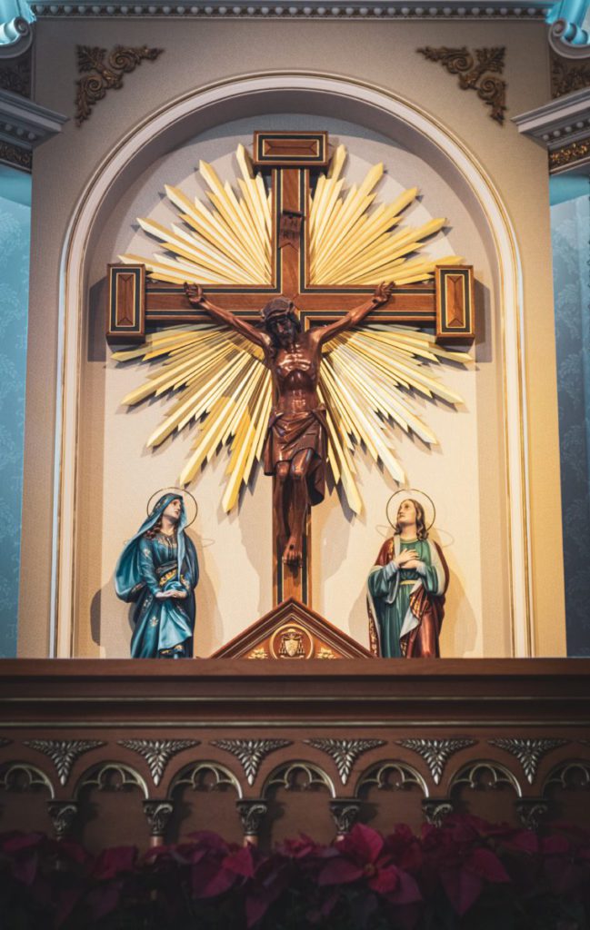 crucifix beside religious statues inside building