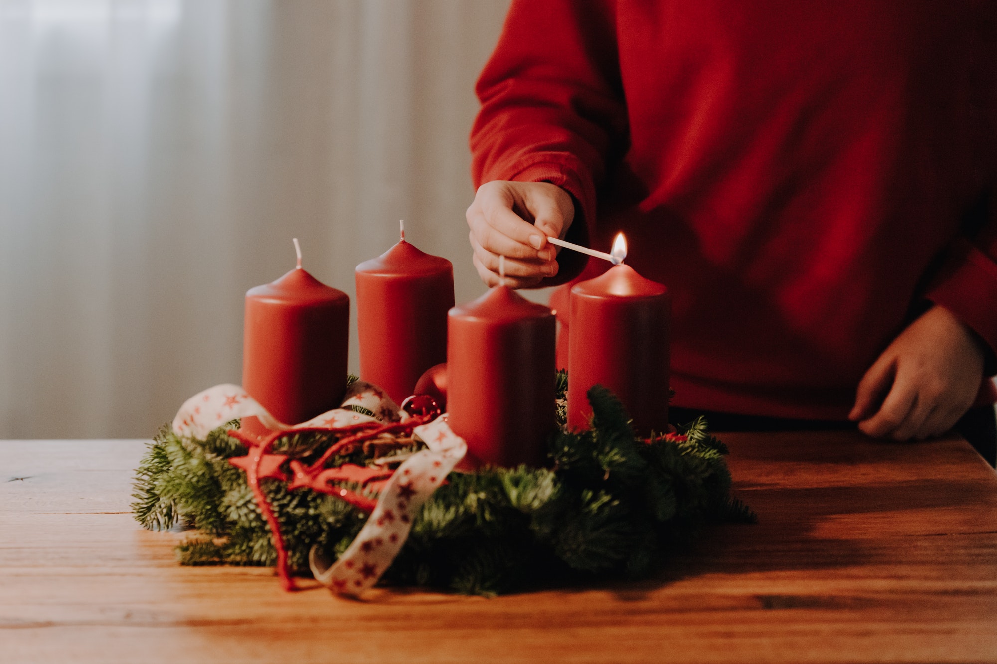 Child hand lighting the first candle of Advent Wreath on the first Advent Sunday.